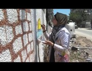 فتاة فلسطينية ترسم على جدران المباني المدمرة في غزة