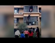 عامل توصيل صيني يتسلق مبنى لإنقاذ أسرة من حريق