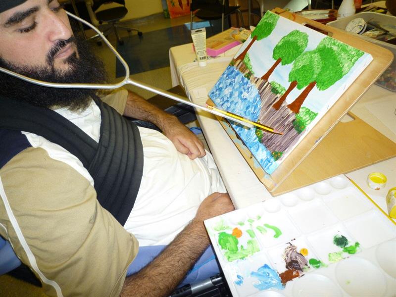 بعد إصابته بشلل رباعي.. شاب سعودي يُبدع في رسم لوحاته برأسه (صور)