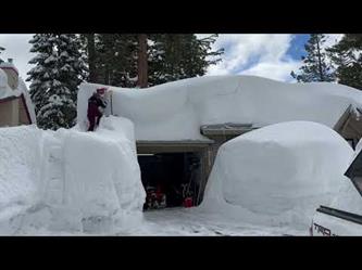 امرأة تحاول التخلص من كميات ضخمة من الثلوج غطت منزلها